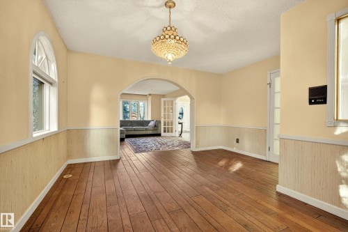 Spacious interior featuring wood-finish flooring, a tiered crystal chandelier, and arched doorways - 33 Glen Meadow Crescent, St. Albert, AB - Indoor Photo Showing Other Room