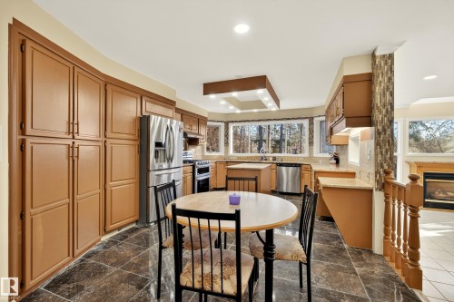 Kitchen featuring extensive cabinetry, stainless steel appliances, dark stone-finish tile flooring, recessed lighting, and a bay window overlooking exterior trees - 33 Glen Meadow Crescent, St. Albert, AB - Indoor Photo Showing Other Room