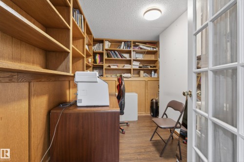 Room featuring extensive built-in wooden shelving, wood paneling, wood-finish flooring, and a flush-mount ceiling light - 33 Glen Meadow Crescent, St. Albert, AB - Indoor Photo Showing Other Room