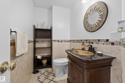 Bathroom featuring a dark wood vanity with a gold-tone basin, a dark countertop, and matte black fixtures - 33 Glen Meadow Crescent, St. Albert, AB - Indoor Photo Showing Bathroom