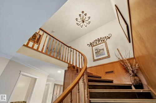 Curved wooden staircase with dark treads and light wood risers, featuring a turned wood baluster railing - 33 Glen Meadow Crescent, St. Albert, AB - Indoor Photo Showing Other Room