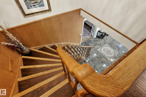 Curved staircase featuring wood-finish treads, a solid wood handrail, and wood paneling - 33 Glen Meadow Crescent, St. Albert, AB - Indoor Photo Showing Other Room