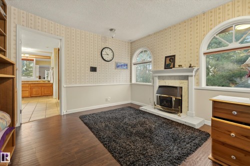 Room featuring a fireplace with a stone surround and white mantel, flanked by two arched windows - 33 Glen Meadow Crescent, St. Albert, AB - Indoor With Fireplace