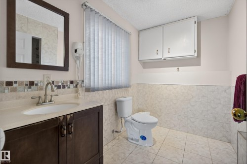 Bathroom featuring a vanity with dark wood-finish cabinetry, light-toned countertop, and undermount sink - 33 Glen Meadow Crescent, St. Albert, AB - Indoor Photo Showing Bathroom