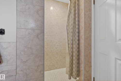 Tiled shower enclosure featuring light-toned large format wall tiles and a grid pattern floor - 33 Glen Meadow Crescent, St. Albert, AB - Indoor Photo Showing Bathroom