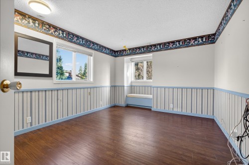Spacious room featuring wood-finish flooring, white walls with blue and white striped wainscoting, and a decorative border - 33 Glen Meadow Crescent, St. Albert, AB - Indoor Photo Showing Other Room