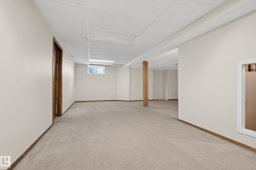 Expansive finished lower level featuring neutral carpet, light-toned walls, a drop ceiling, a small window, and a wood support column - 33 Glen Meadow Crescent, St. Albert, AB - Indoor