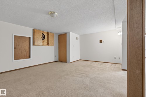 Carpeted room with white walls, a visible wall-mounted cabinet, and two wood-paneled doors - 33 Glen Meadow Crescent, St. Albert, AB - Indoor Photo Showing Other Room