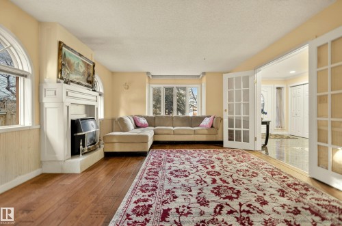 Living area featuring wood-finish flooring and a decorative fireplace with a white mantel - 33 Glen Meadow Crescent, St. Albert, AB - Indoor Photo Showing Living Room With Fireplace