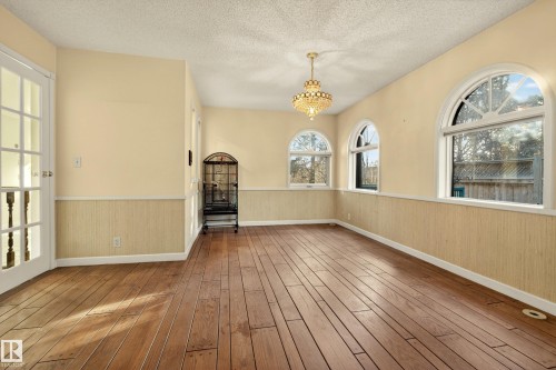Interior room featuring wood-finish flooring, three arched windows, and a decorative chandelier - 33 Glen Meadow Crescent, St. Albert, AB - Indoor Photo Showing Other Room