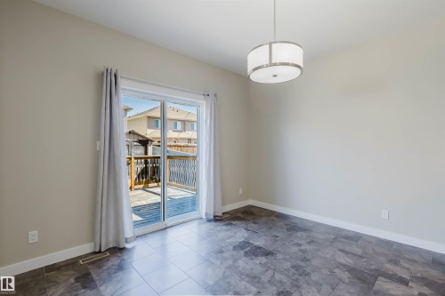 Spacious room featuring neutral wall tones, large format tile flooring, and a contemporary drum pendant light fixture - 611 176 Street, Edmonton, AB - Indoor Photo Showing Other Room