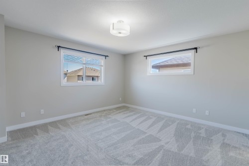 Bedroom featuring two windows with white frames, light gray walls, a patterned gray carpet, and a flush mount ceiling light fixture - 611 176 Street, Edmonton, AB - Indoor Photo Showing Other Room