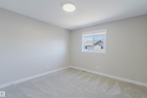 Carpeted room featuring a single window with blinds, a flush-mount ceiling light, and light-toned walls with white trim - 611 176 Street, Edmonton, AB - Indoor Photo Showing Other Room