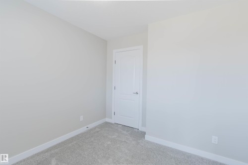 Neutral-toned wall finish, white baseboards, and light gray carpeting - 611 176 Street, Edmonton, AB - Indoor Photo Showing Other Room