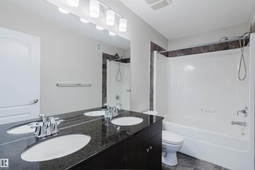 Bathroom featuring a double vanity with stone countertop, two undermount sinks, and chrome faucets - 611 176 Street, Edmonton, AB - Indoor Photo Showing Bathroom