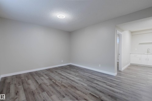 Spacious room with wood-finish flooring, light gray walls, and white trim - 611 176 Street, Edmonton, AB - Indoor Photo Showing Other Room