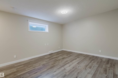 Spacious room featuring wood-finish flooring, light neutral wall paint, and white trim - 611 176 Street, Edmonton, AB - Indoor Photo Showing Other Room
