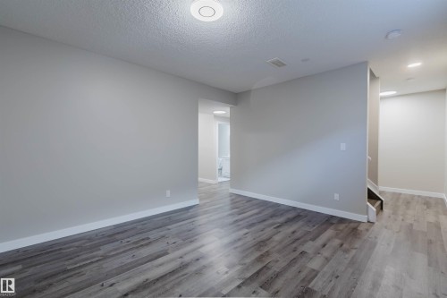 Spacious room with wood-finish flooring, light grey walls, and white baseboards - 611 176 Street, Edmonton, AB - Indoor Photo Showing Other Room