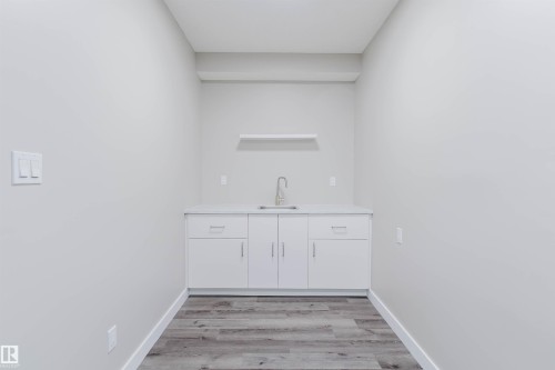 Dedicated utility space featuring a white base cabinet with a single basin sink, light-colored countertop, and a wall-mounted shelf - 611 176 Street, Edmonton, AB - Indoor Photo Showing Other Room