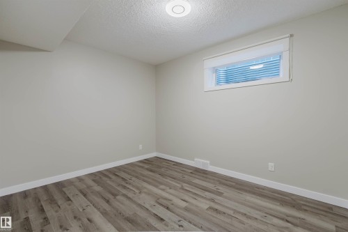 Spacious room featuring wood-finish flooring, white baseboards, and a neutral wall color - 611 176 Street, Edmonton, AB - Indoor Photo Showing Other Room