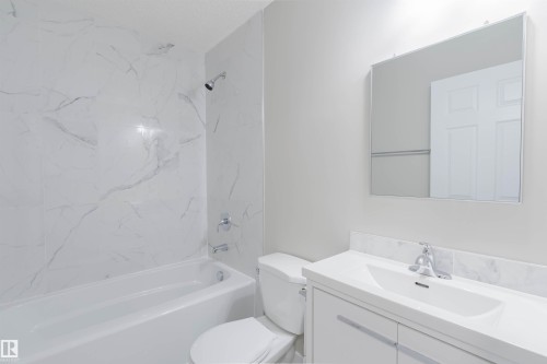 Bathroom featuring a white bathtub, toilet, and vanity with an integrated sink - 611 176 Street, Edmonton, AB - Indoor Photo Showing Bathroom
