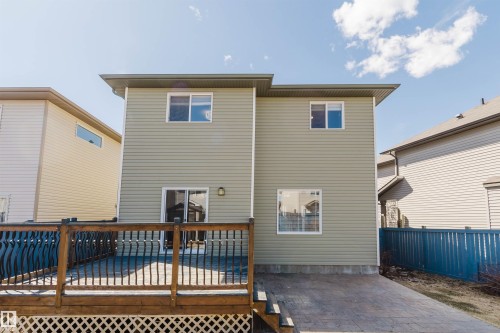 Rear exterior featuring a spacious wood deck with dark balusters, paver patio, and light green vinyl siding - 611 176 Street, Edmonton, AB - Outdoor With Deck Patio Veranda With Exterior