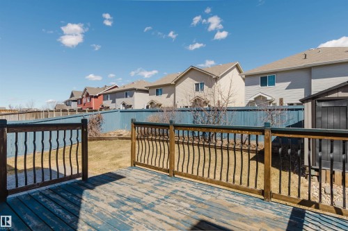 Expansive backyard featuring a blue-painted wooden deck with decorative railing, a storage shed, and a privacy fence - 611 176 Street, Edmonton, AB - Outdoor With Exterior