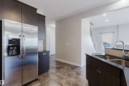 Kitchen featuring a stainless steel side-by-side refrigerator, dark cabinetry, and a double basin sink - 611 176 Street, Edmonton, AB - Indoor Photo Showing Kitchen With Double Sink