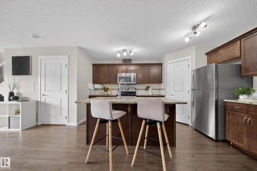 The property features a kitchen with dark wood cabinetry, stainless steel appliances, and granite countertops - 2118 52A Street, Edmonton, AB - Indoor Photo Showing Kitchen