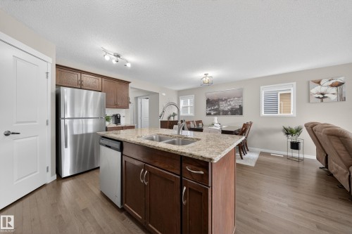 The property features a kitchen with dark wood cabinetry, granite countertops, and stainless steel appliances, including a refrigerator and dishwasher - 2118 52A Street, Edmonton, AB - Indoor Photo Showing Kitchen With Double Sink