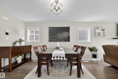 This open-concept dining area features hardwood floors, light-colored walls, and a contemporary light fixture - 2118 52A Street, Edmonton, AB - Indoor Photo Showing Dining Room
