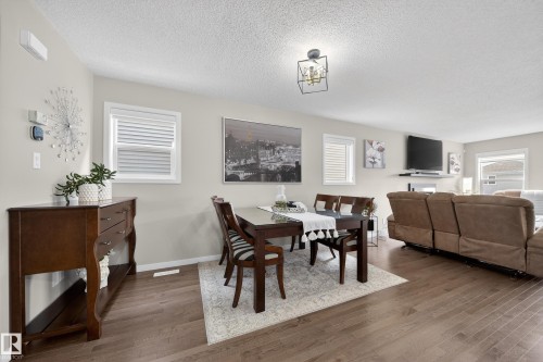 This open concept living space features hardwood flooring, light grey walls, and a contemporary ceiling light fixture - 2118 52A Street, Edmonton, AB - Indoor