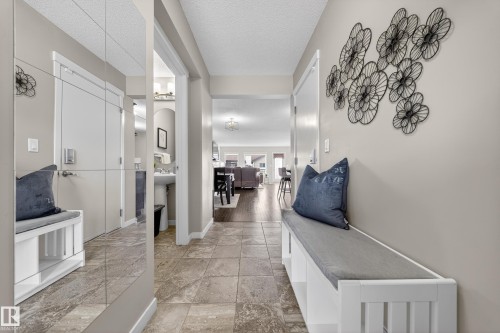 The entry features tiled flooring, a built-in bench with a cushion, and a mirrored wall - 2118 52A Street, Edmonton, AB - Indoor Photo Showing Other Room