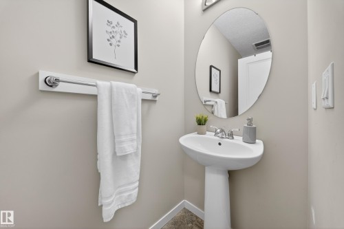 Bathroom featuring a pedestal sink, an oval mirror, and a wall-mounted towel bar - 2118 52A Street, Edmonton, AB - Indoor Photo Showing Bathroom
