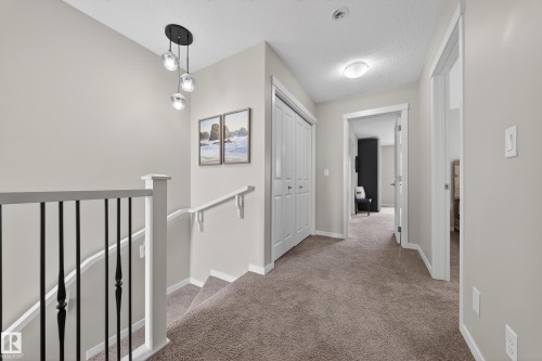 The property features a staircase with a black metal railing and a modern ceiling light fixture - 2118 52A Street, Edmonton, AB - Indoor Photo Showing Other Room