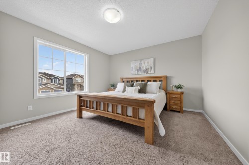 This bedroom features a large window providing natural light, neutral-toned walls, and plush carpeting - 2118 52A Street, Edmonton, AB - Indoor Photo Showing Bedroom