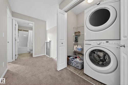 Convenient laundry area featuring a stacked washer and dryer, accompanied by shelving for storage - 2118 52A Street, Edmonton, AB - Indoor Photo Showing Laundry Room