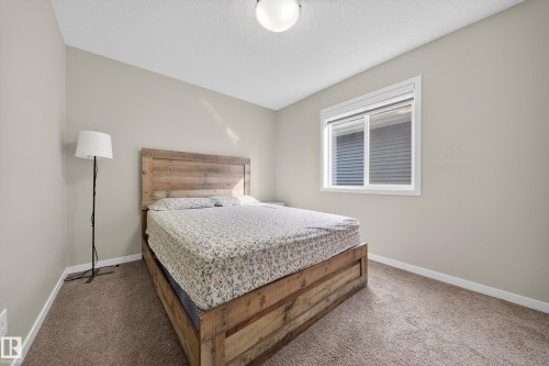 This room features neutral-toned walls, carpeted flooring, and a window with blinds providing natural light - 2118 52A Street, Edmonton, AB - Indoor Photo Showing Bedroom