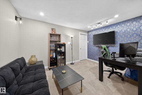 This versatile room features carpeted flooring, recessed lighting, and a prominent accent wall with blue and white patterned wallpaper - 2118 52A Street, Edmonton, AB - Indoor Photo Showing Office