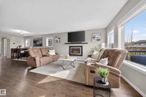 This open concept living space features hardwood floors, large windows providing natural light, and a modern fireplace - 2118 52A Street, Edmonton, AB - Indoor Photo Showing Living Room With Fireplace