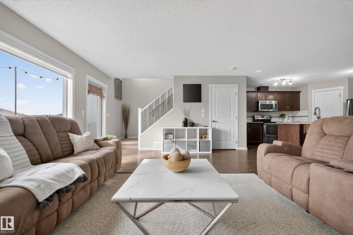 The open-concept living area features a kitchen with dark wood cabinetry and stainless steel appliances - 2118 52A Street, Edmonton, AB - Indoor Photo Showing Living Room