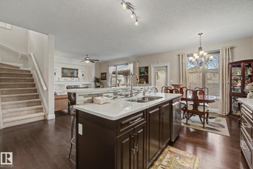 Kitchen island with white countertop, dual sinks, and dark wood-finish cabinetry - 805 Hodgins Road, Edmonton, AB - Indoor Photo Showing Kitchen With Double Sink
