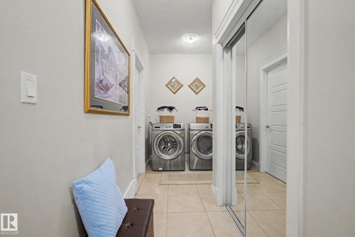 Laundry area featuring tile flooring, a mirrored closet door, and overhead lighting - 805 Hodgins Road, Edmonton, AB - Indoor Photo Showing Laundry Room