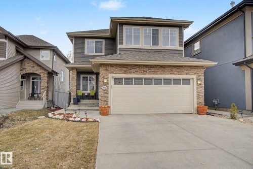 Two-story residence featuring a stone and siding exterior, an attached two-car garage with transom windows, a concrete driveway, and a covered front porch - 805 Hodgins Road, Edmonton, AB - Outdoor With Facade
