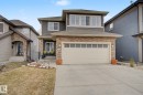 Two-story residence featuring a stone and siding exterior, an attached two-car garage with transom windows, a concrete driveway, and a covered front porch - 805 Hodgins Road, Edmonton, AB  - Outdoor With Facade 