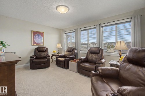 Carpeted interior space featuring a row of three windows with horizontal blinds and drapery rods - 805 Hodgins Road, Edmonton, AB - Indoor Photo Showing Living Room