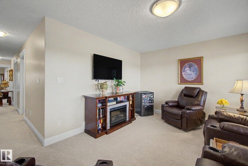 Carpeted living area featuring a built-in media console with an electric fireplace, light-toned walls, and a ceiling-mounted light fixture - 805 Hodgins Road, Edmonton, AB - Indoor Photo Showing Living Room
