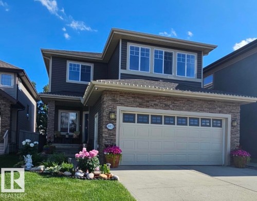 Two-story dwelling featuring stone and siding exterior, an attached garage with window inserts, a concrete driveway, and a front entry with a small porch - 805 Hodgins Road, Edmonton, AB - Outdoor With Facade