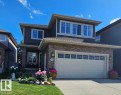 Two-story dwelling featuring stone and siding exterior, an attached garage with window inserts, a concrete driveway, and a front entry with a small porch - 805 Hodgins Road, Edmonton, AB  - Outdoor With Facade 