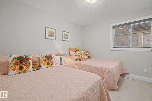 Light gray painted walls with a textured ceiling and neutral carpet flooring - 805 Hodgins Road, Edmonton, AB - Indoor Photo Showing Bedroom
